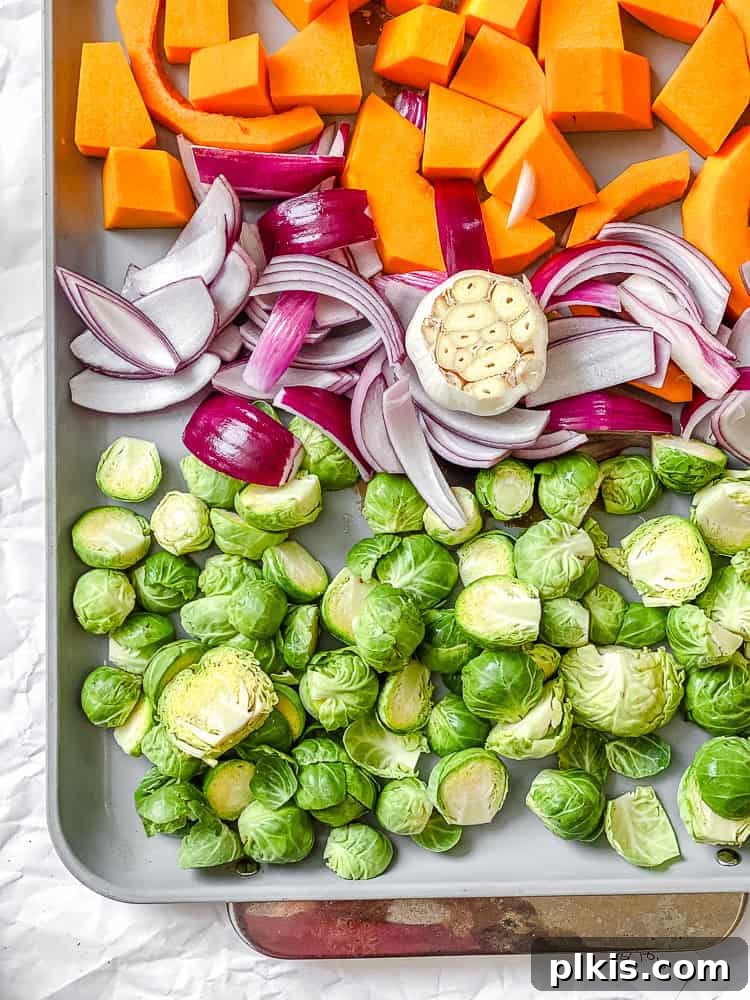 Golden Harvest Quinoa Salad 4 Process shot showing Brussels sprouts, butternut squash, and red onion spread out on a baking tray.
