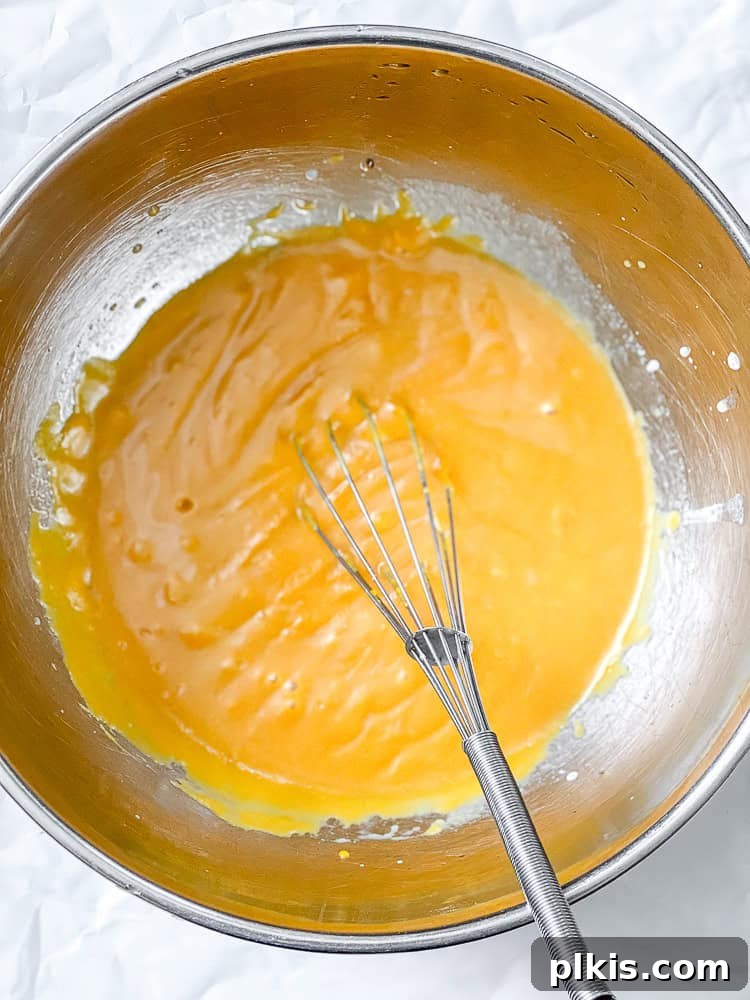 Spiced Butternut Delight 5 Process shot showing a large mixing bowl with wet ingredients and butternut squash puree being whisked together to form a smooth batter.