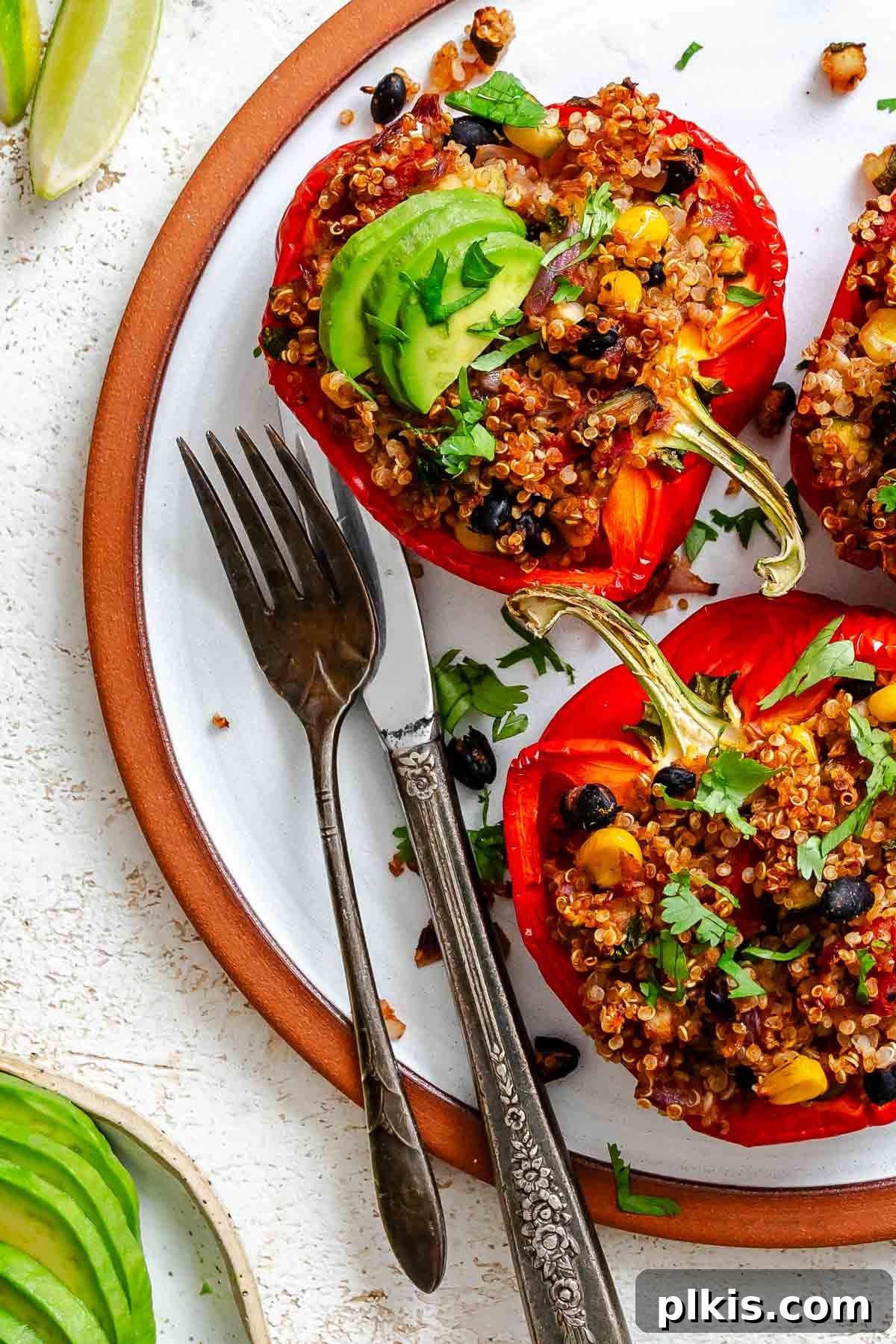 Wholesome Quinoa Stuffed Peppers 2 Completed Quinoa Stuffed Bell Peppers on a plate, garnished with fresh cilantro and avocado.