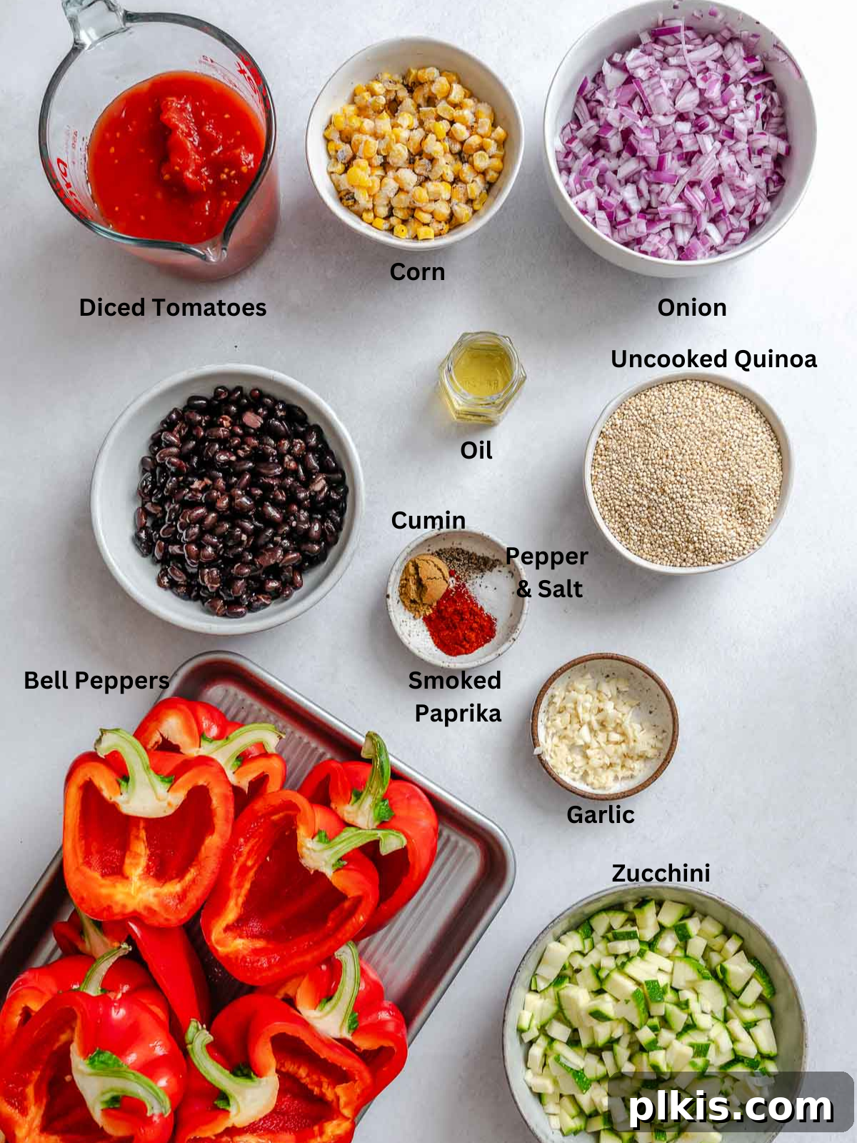 Wholesome Quinoa Stuffed Peppers 3 Ingredients for Quinoa Stuffed Bell Peppers measured out on a white surface, including quinoa, bell peppers, canned goods, and spices.