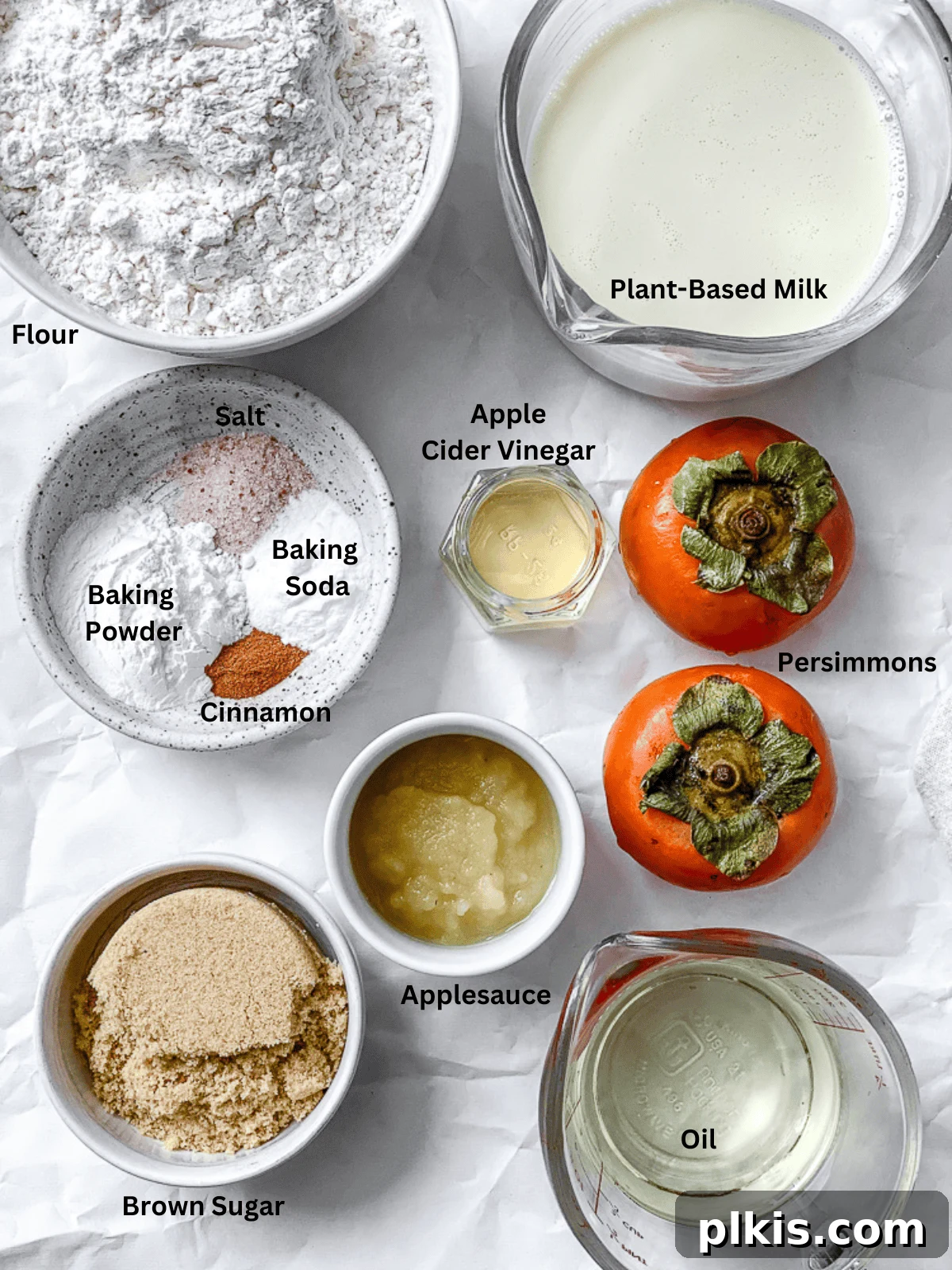 Simple Spiced Persimmon Muffins 3 A collection of measured ingredients for Easy Persimmon Muffins displayed neatly on a clean white surface, including diced persimmons, flour, sugar, plant milk, applesauce, and spices.
