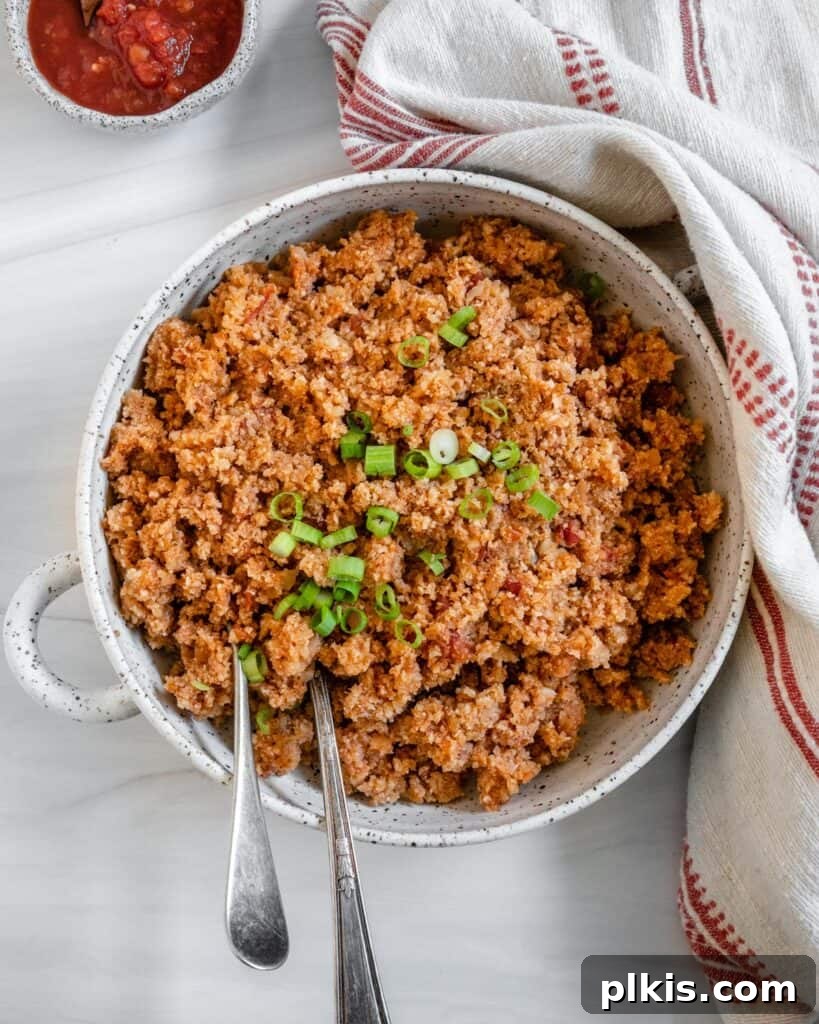 Quick and Flavorful Spanish Cauliflower Rice Bowl with Salsa 2 completed Spanish Cauliflower Rice in a white bowl against a white surface with two utensils in the bowl