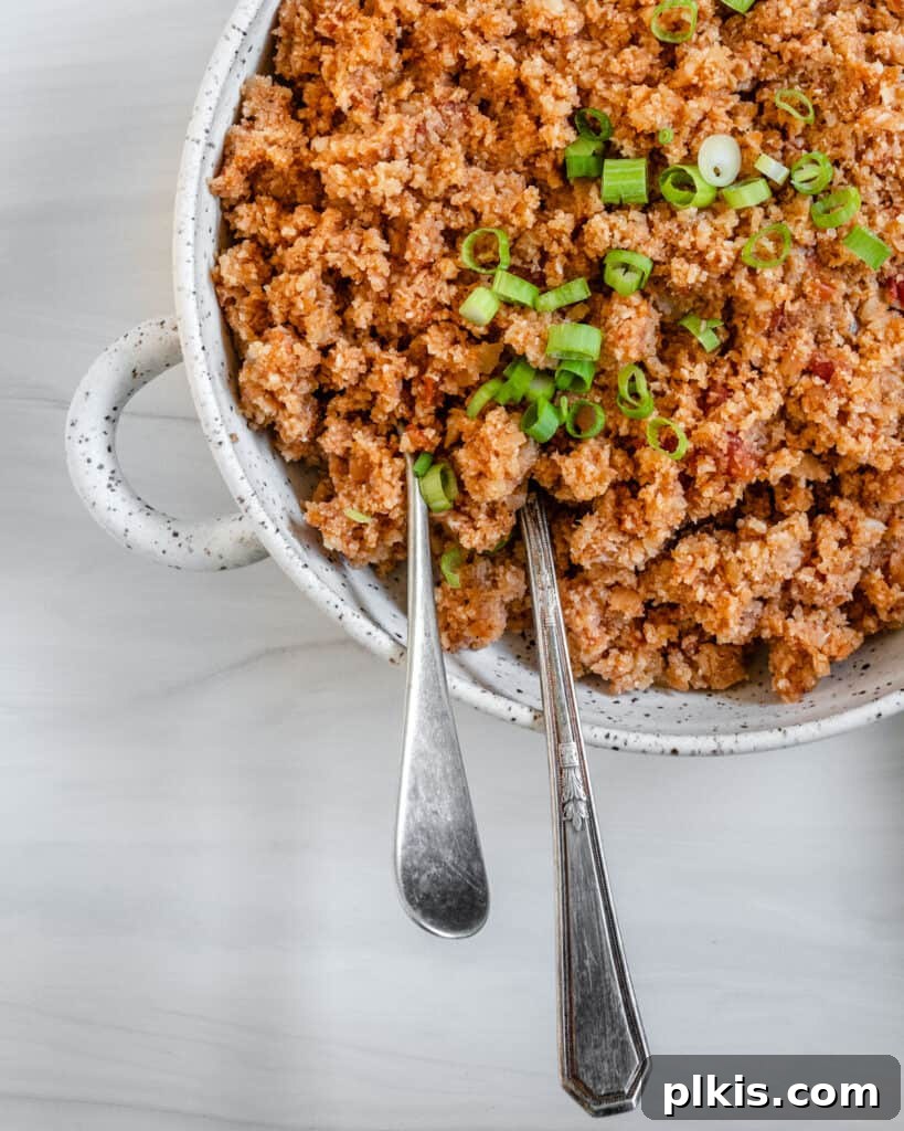 Quick and Flavorful Spanish Cauliflower Rice Bowl with Salsa 12 completed Spanish Cauliflower Rice in a white bowl against a white surface with two utensils in the bowl