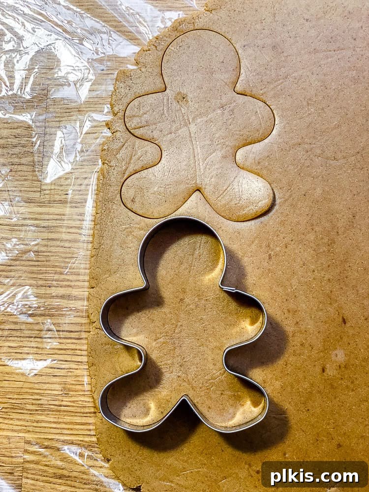 Cozy Vegan Gingerbread Delights 8 Process shot showing gingerbread men shapes cut out from the rolled dough using cookie cutters.