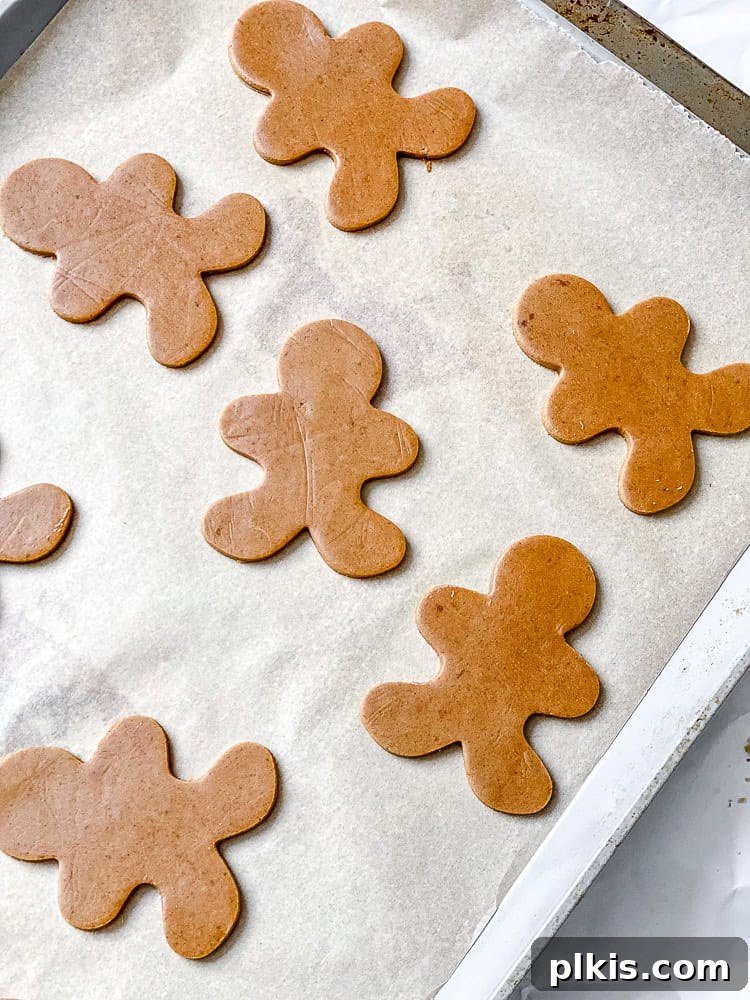 Cozy Vegan Gingerbread Delights 9 Process shot showing cut-out gingerbread men placed on a parchment-lined baking sheet, ready for baking.