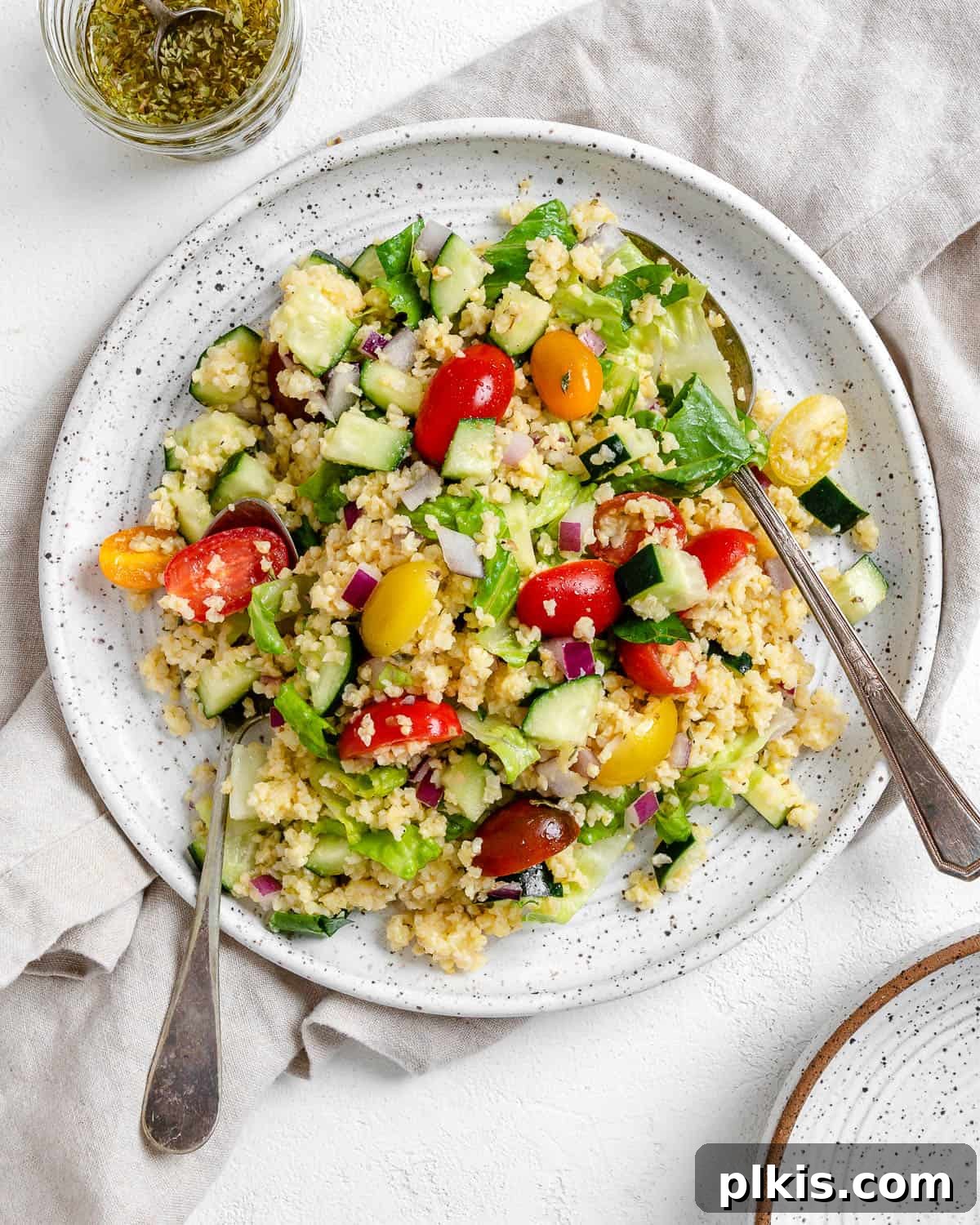 Vibrant Vegan Greek Millet Bowl 2 A beautifully arranged completed Vegan Greek Millet Salad on a pristine white plate, set against a soft, light background. The salad is vibrant with fresh vegetables and golden millet.