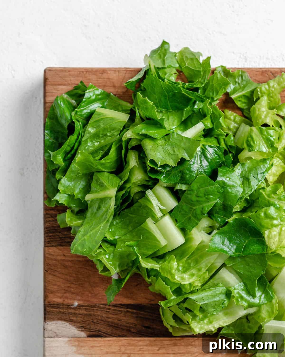 Vibrant Vegan Greek Millet Bowl 11 Freshly chopped Romaine lettuce, bright green and ready, piled neatly on a wooden cutting board.
