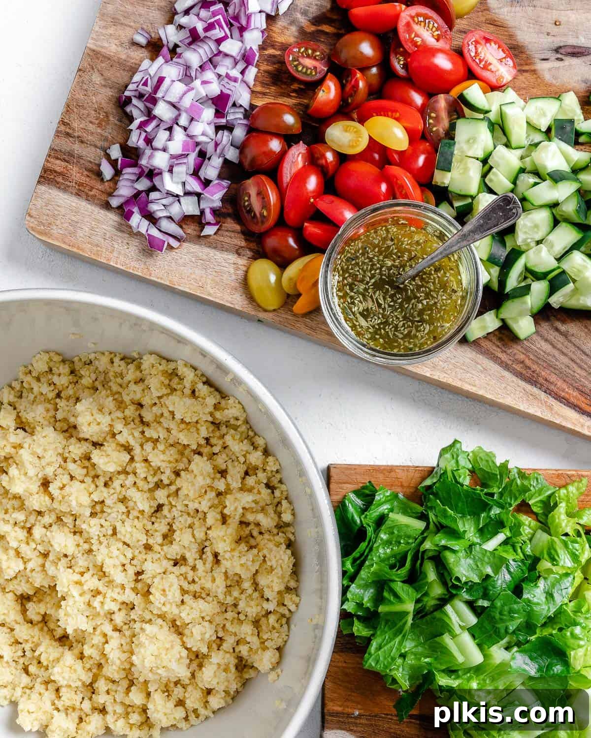 Vibrant Vegan Greek Millet Bowl 12 An array of chopped and cooked ingredients for the Vegan Greek Millet Salad, including millet, vegetables, and dressing, displayed on a cutting board.