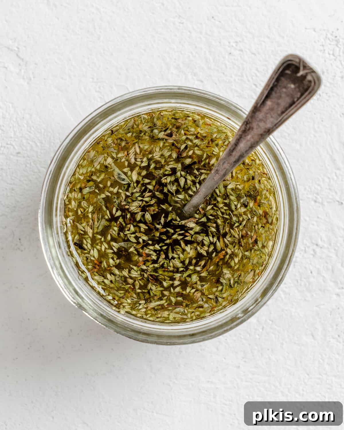 Vibrant Vegan Greek Millet Bowl 6 A close-up view of the dressing ingredients being vigorously mixed in a small white bowl, showing the texture and color of the whisked liquid.