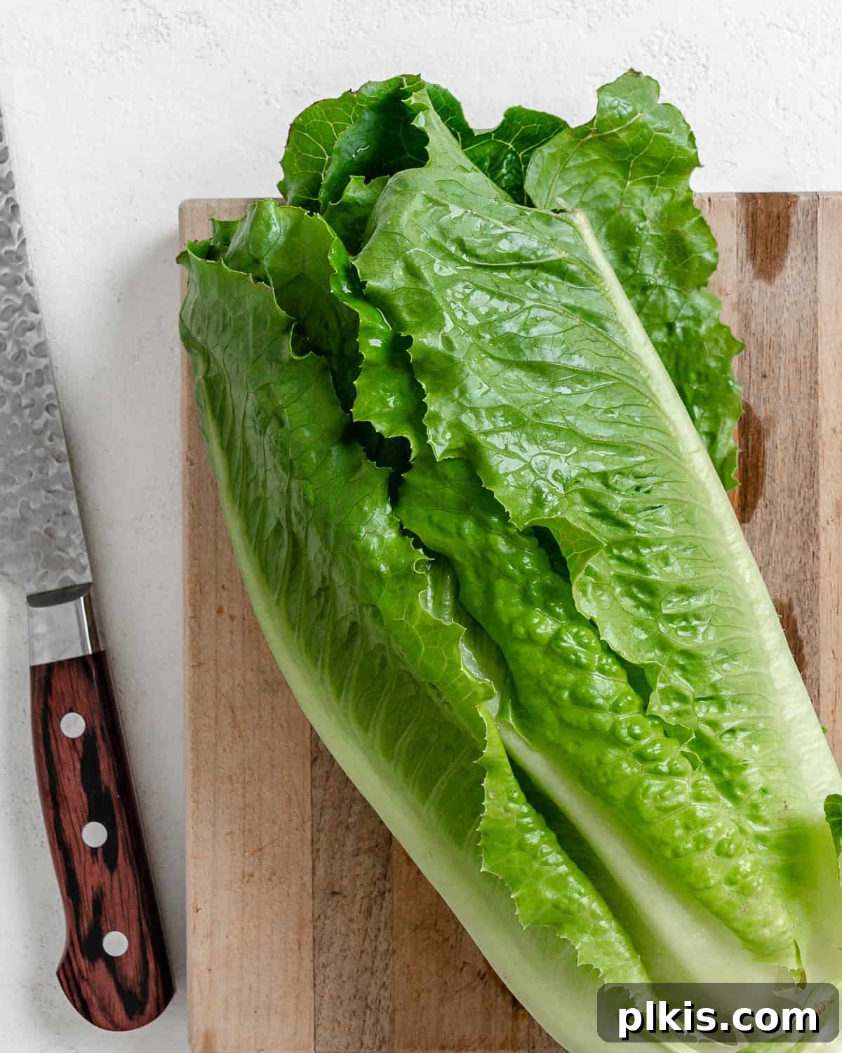 Vibrant Vegan Greek Millet Bowl 10 Crisp Romaine lettuce leaves laid out on a cutting board, with a chef's knife in the background, signaling preparation.