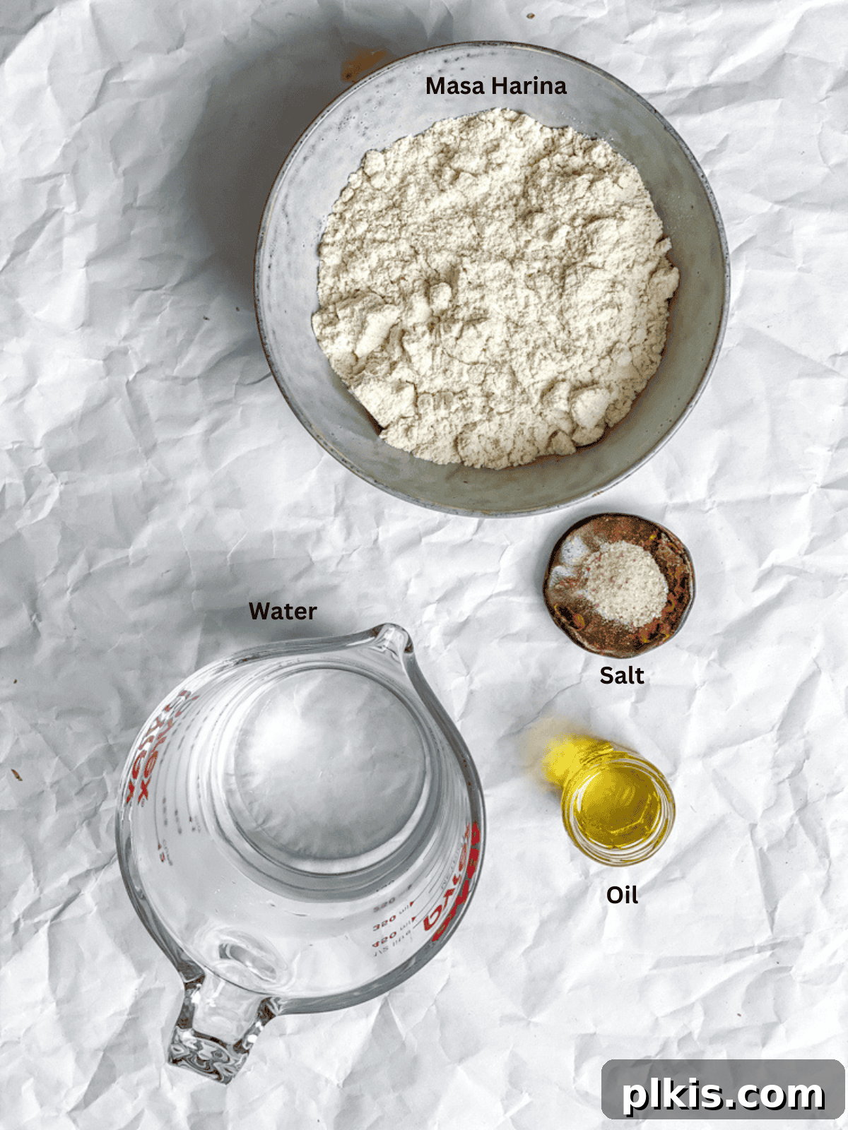 Crafting Perfect Corn Tortillas at Home 3 All the measured ingredients for Homemade Corn Tortillas including masa harina, salt, and warm water are laid out on a white kitchen surface.
