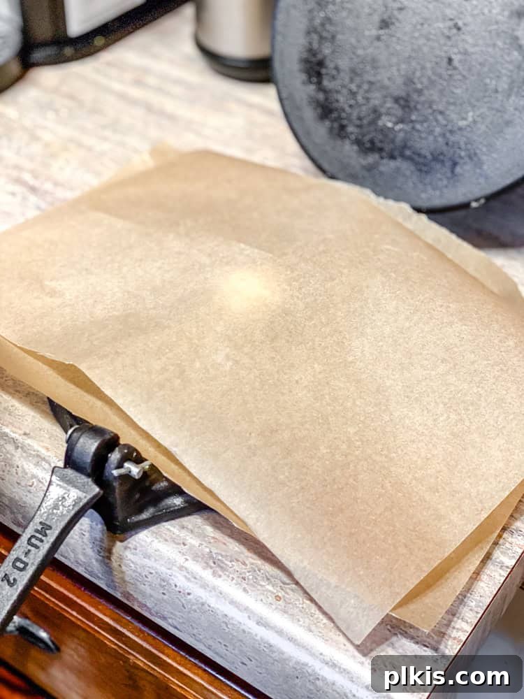Crafting Perfect Corn Tortillas at Home 6 A process shot showing a dough ball placed between two sheets of parchment paper, ready to be pressed into a tortilla.