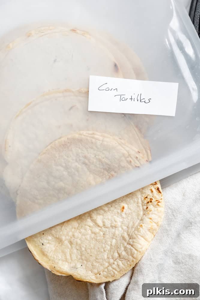 Crafting Perfect Corn Tortillas at Home 9 A neatly stacked pile of homemade corn tortillas stored in a clear, airtight container, showcasing excellent meal prep.