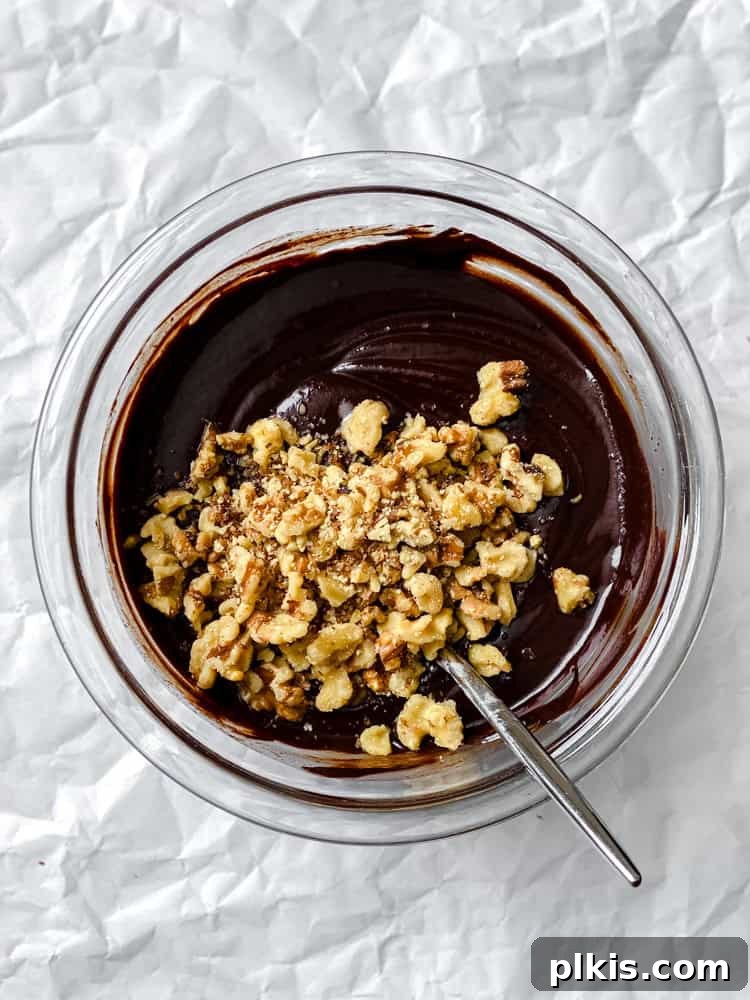 Easy Microwave Vegan Fudge 5 process shot showing mixing walnuts into bowl of chocolate