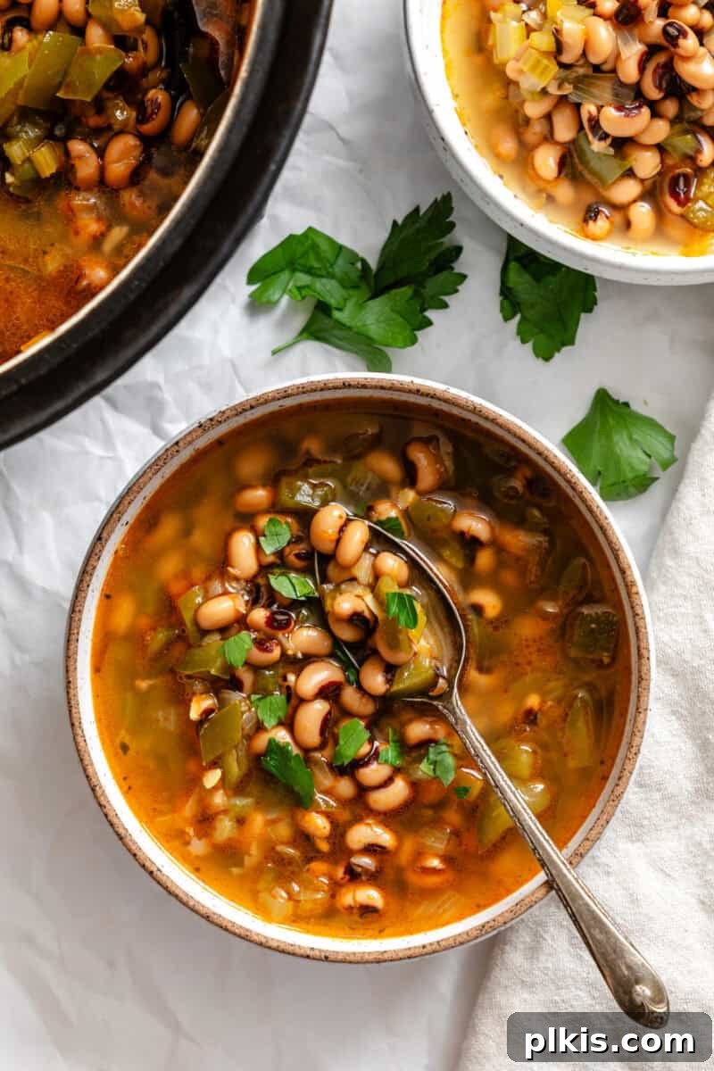 Soulful Vegan Black Eyed Pea Soup 2 A steaming bowl of completed Vegan Black Eyed Pea Soup, garnished with fresh parsley, next to the rustic cooking pot.
