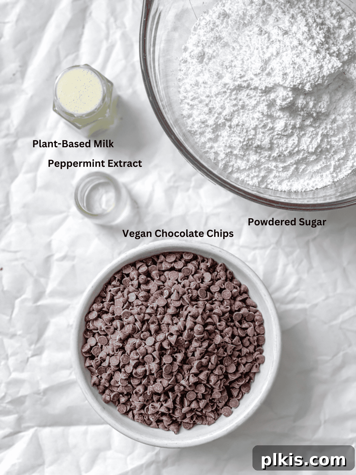 Cool Mint Vegan Delights 3 Individual ingredients for Vegan Peppermint Patties laid out on a white surface, including powdered sugar, plant-based milk, peppermint extract, and vegan chocolate chips.