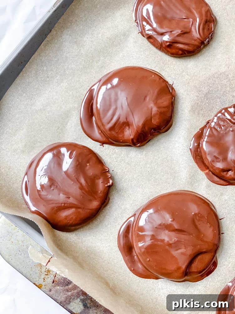 Cool Mint Vegan Delights 7 Process shot showing chocolate-coated vegan peppermint patties cooling and setting on a parchment-lined baking sheet.