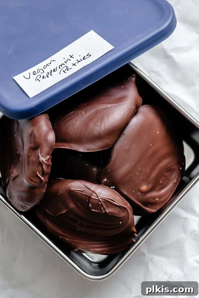 Cool Mint Vegan Delights 9 Several completed Vegan Peppermint Patties neatly stacked within a clear, airtight storage container, ready for refrigeration or freezing.