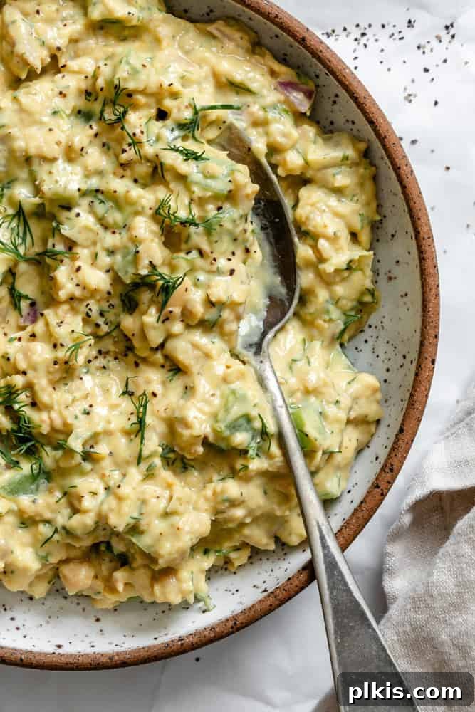 A beautifully plated serving of Easy Curried Chickpea Salad, garnished with fresh herbs and a sprinkle of paprika, invitingly presented on a clean white plate, ready to be savored as a delicious and healthy meal.