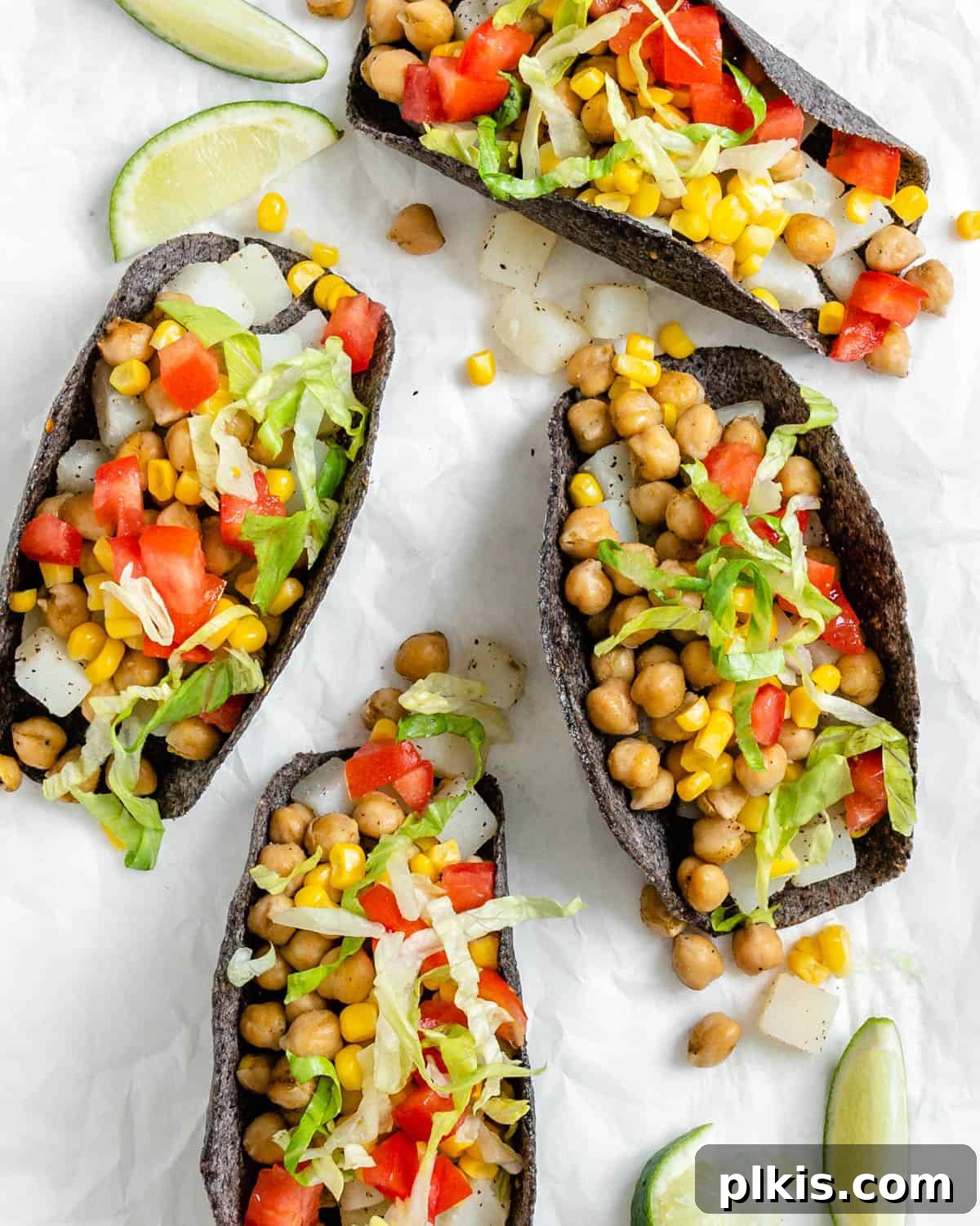 Golden Potato and Chickpea Tacos 2 Four completed Potato and Chickpea Tacos artfully arranged on a clean white surface, garnished with fresh cilantro and a squeeze of lime.