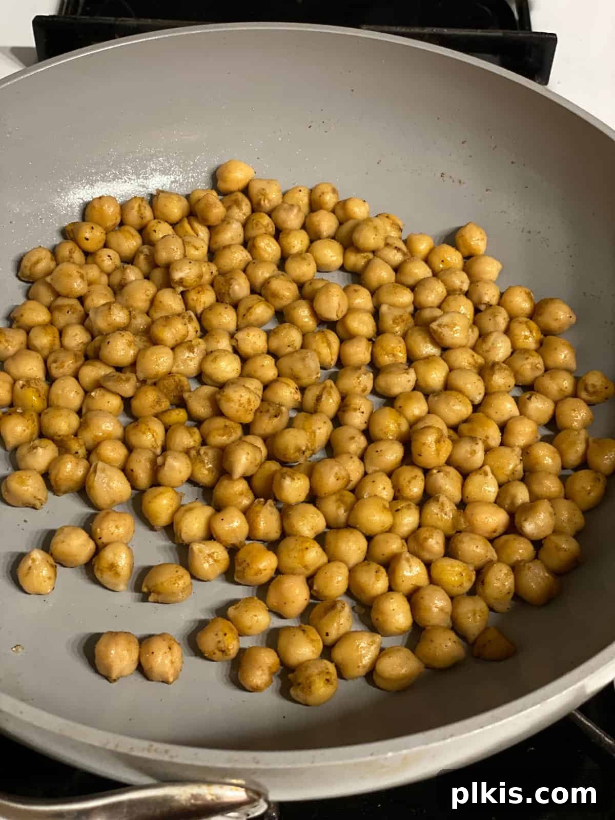 Golden Potato and Chickpea Tacos 10 Process shot of chickpeas being actively cooked and stirred in a frying pan, becoming golden.