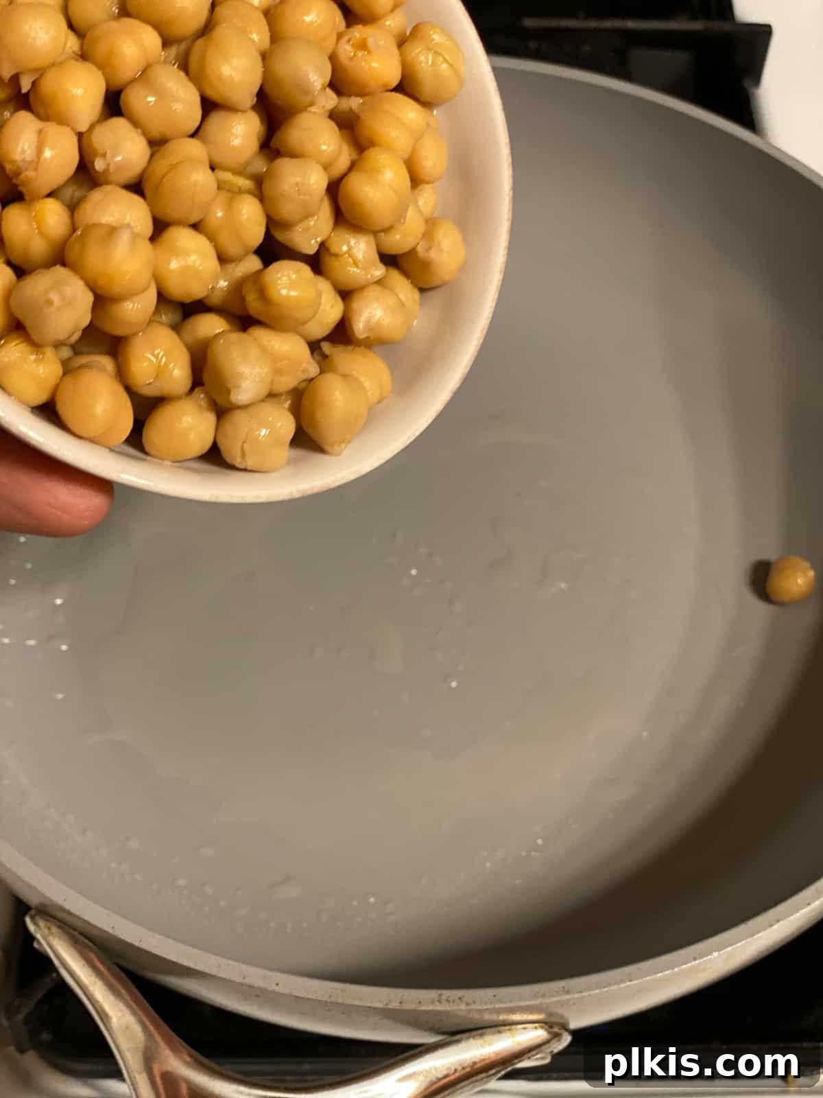 Golden Potato and Chickpea Tacos 8 Process shot of chickpeas being added to a hot frying pan for sautéing.