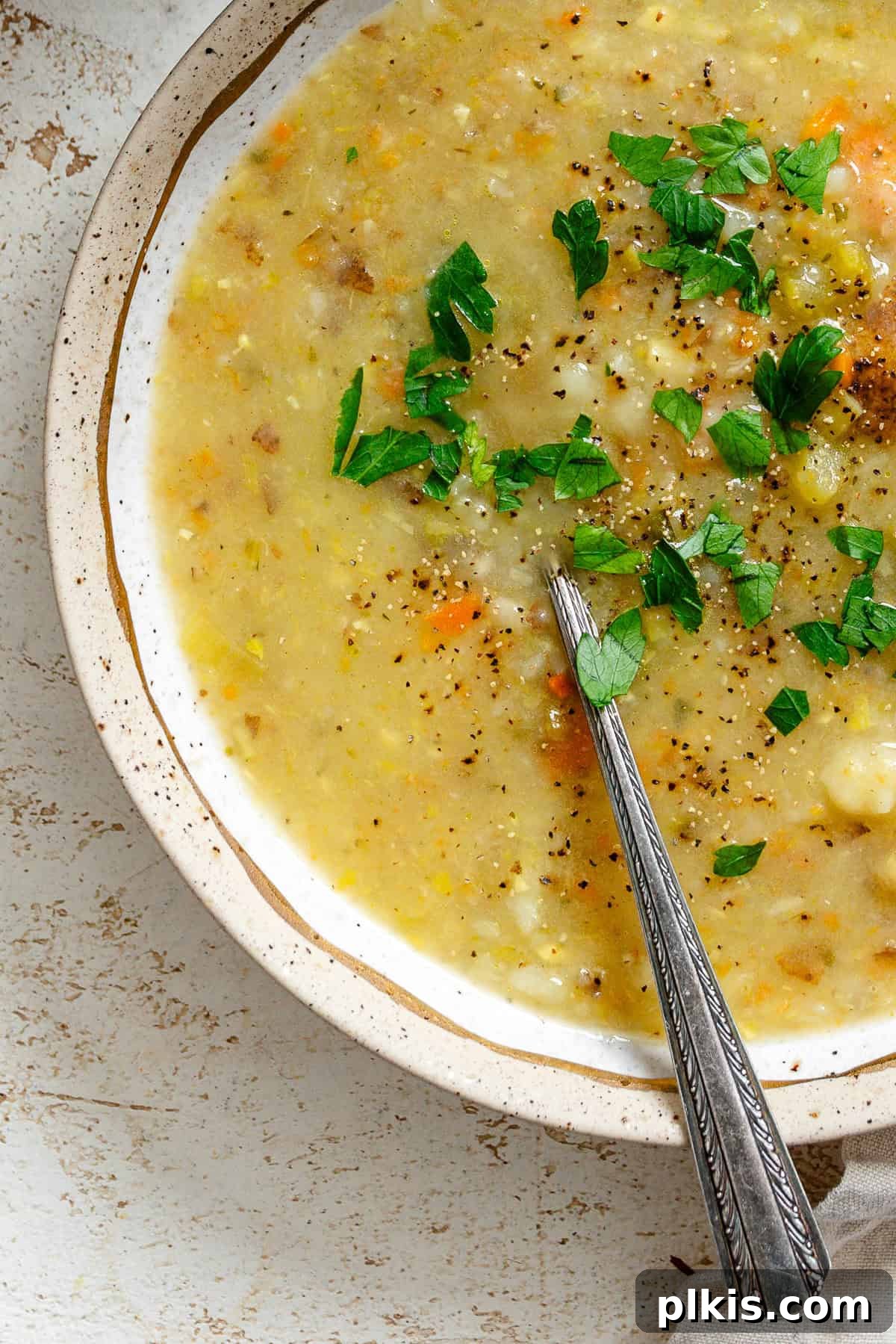 Hearty Vegan Potato and Vegetable Soup 2 A steaming bowl of completed Vegan Potato Soup with fresh herbs and a swirl of cream, filled with visible vegetables.
