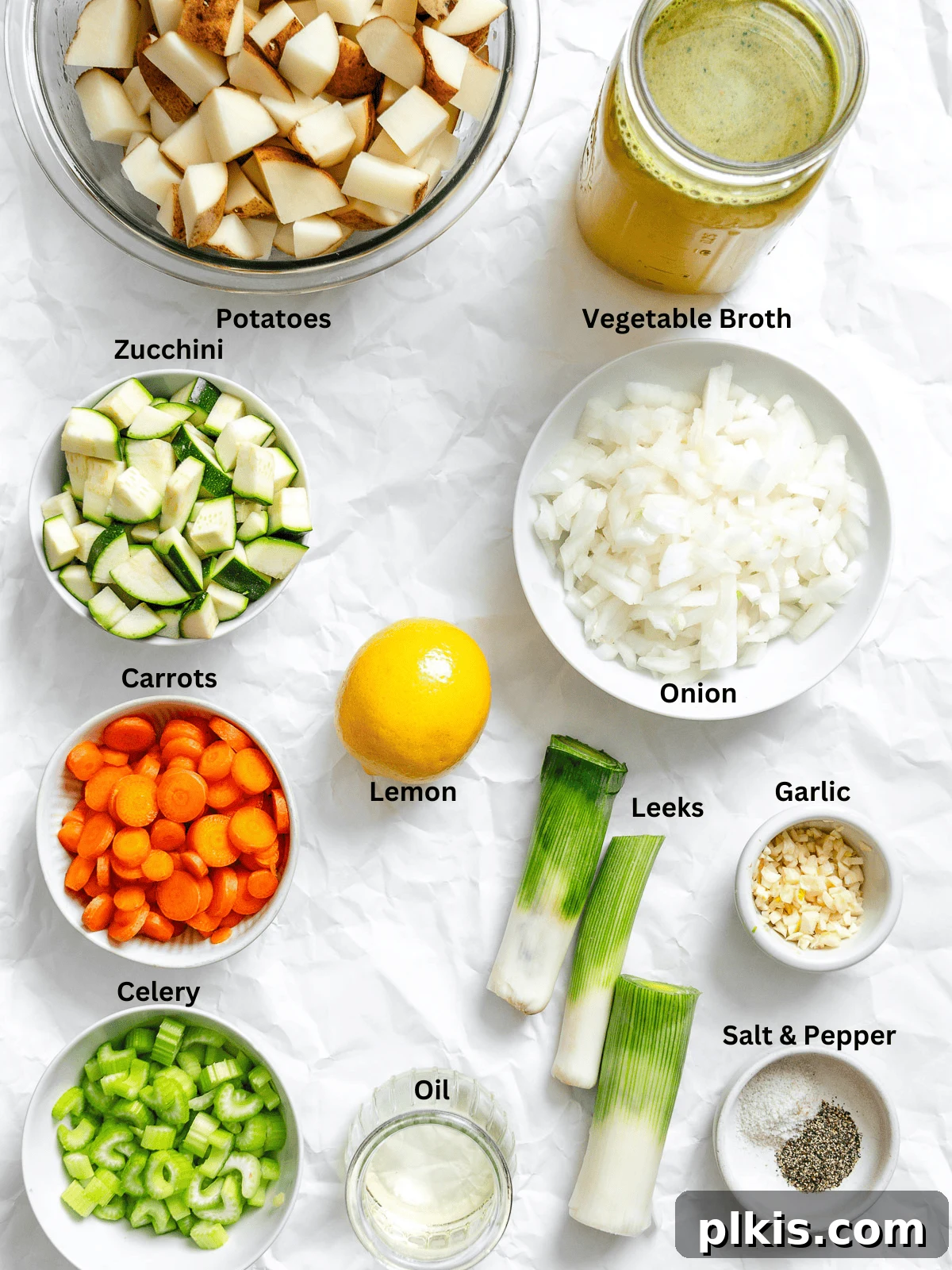 Hearty Vegan Potato and Vegetable Soup 3 Measured out ingredients for Vegan Potato Soup, including diced vegetables, broth, and spices, laid out on a clean white surface.