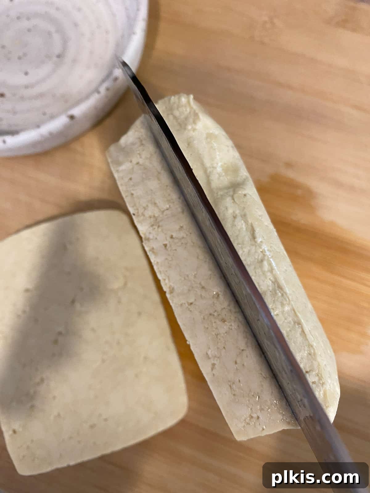 Next-Level Grilled Tofu Steaks 4 Chef slicing a block of tofu horizontally into thick, even slabs on a clean cutting board