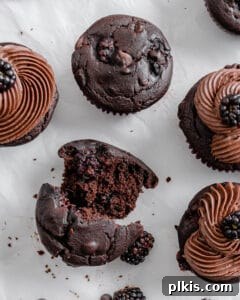 Rich Chocolate Blackberry Delights 11 A completed Vegan Blackberry Chocolate Cupcake crumbled in half on a white surface, revealing its moist interior and berry inclusions.