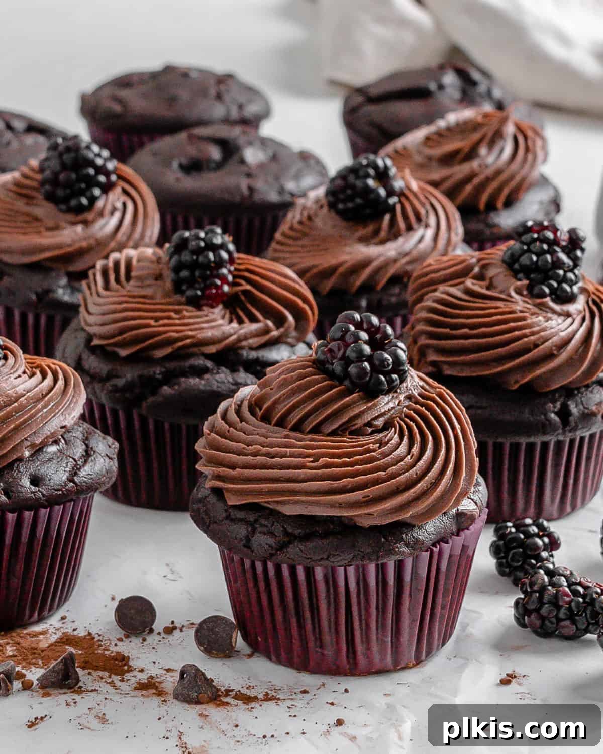 Rich Chocolate Blackberry Delights 13 Close-up of completed Vegan Blackberry Chocolate Cupcakes with fresh blackberries scattered on a white surface, highlighting their delicious appearance.