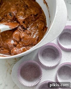 Rich Chocolate Blackberry Delights 8 Process of mixing Vegan Blackberry Chocolate Cupcakes batter with a muffin tin visible in the background.