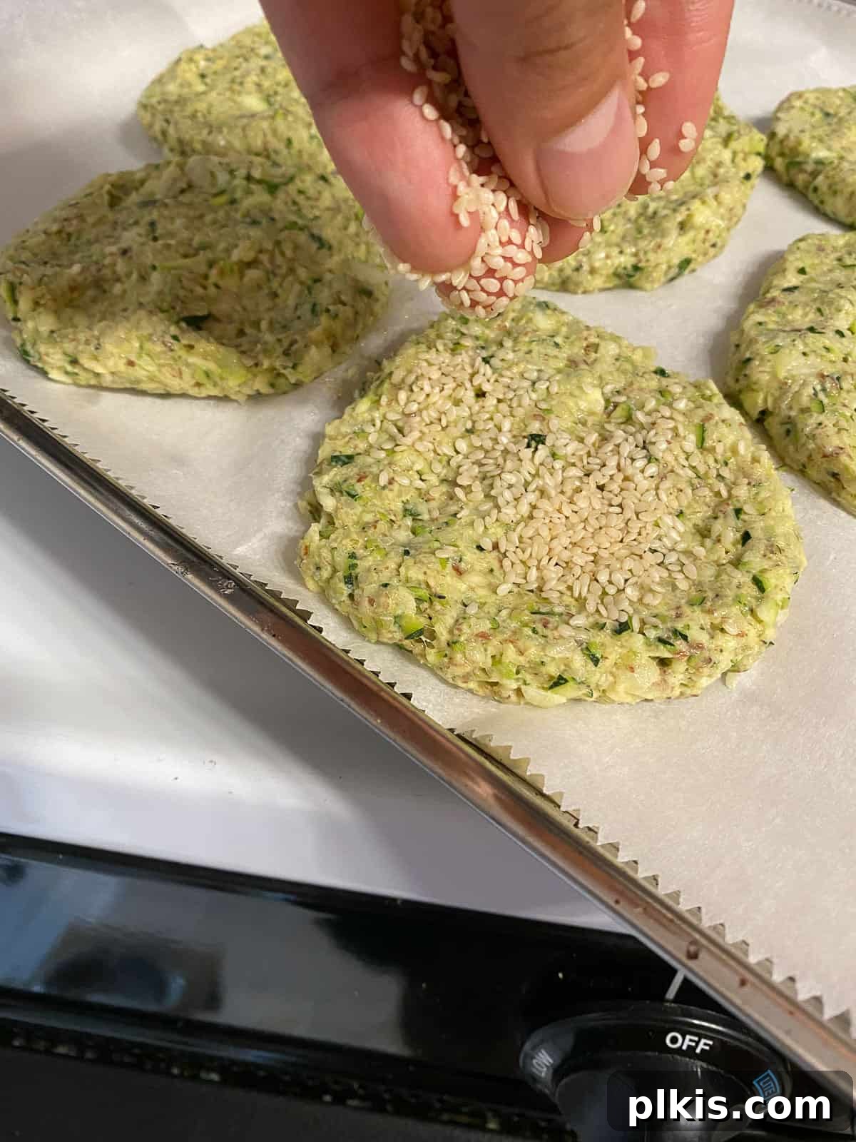 Wholesome Baked Plant-Based Zucchini Fritters 11 process shot of adding sesame seeds to circular shaped zucchini fritters