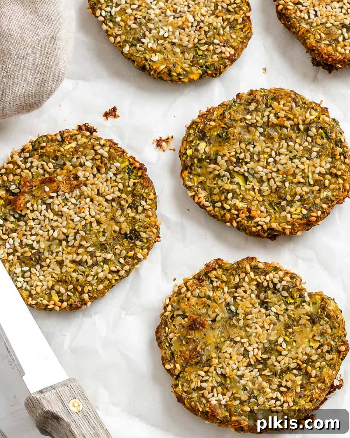 Wholesome Baked Plant-Based Zucchini Fritters 12 completed Vegan Baked Zucchini Fritters against a white surface