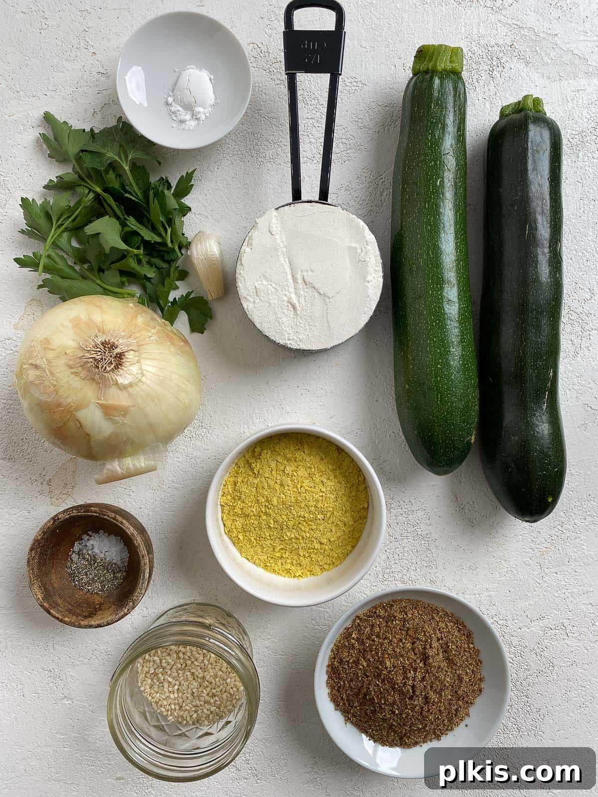 Wholesome Baked Plant-Based Zucchini Fritters 3 ingredients for Vegan Baked Zucchini Fritters measured out and separated on a white surface