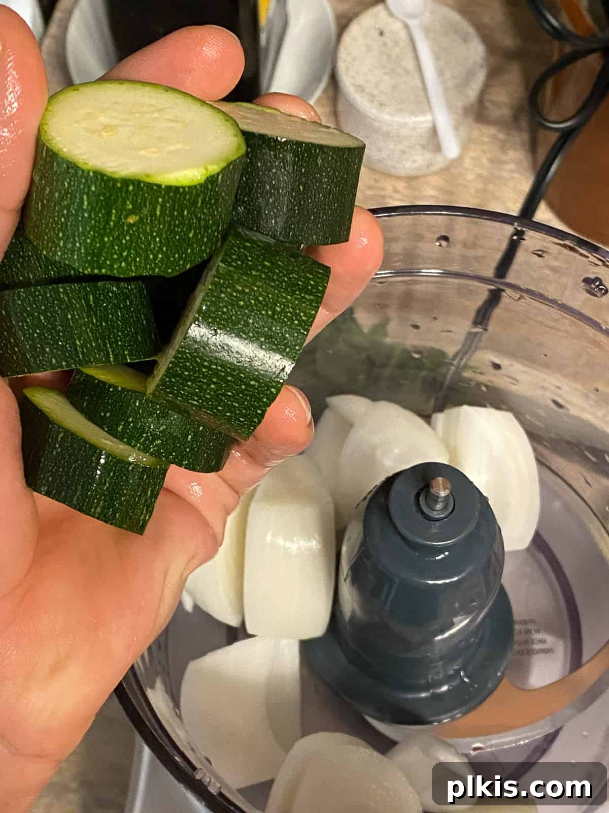 Wholesome Baked Plant-Based Zucchini Fritters 5 process of adding sliced zucchini into food processor
