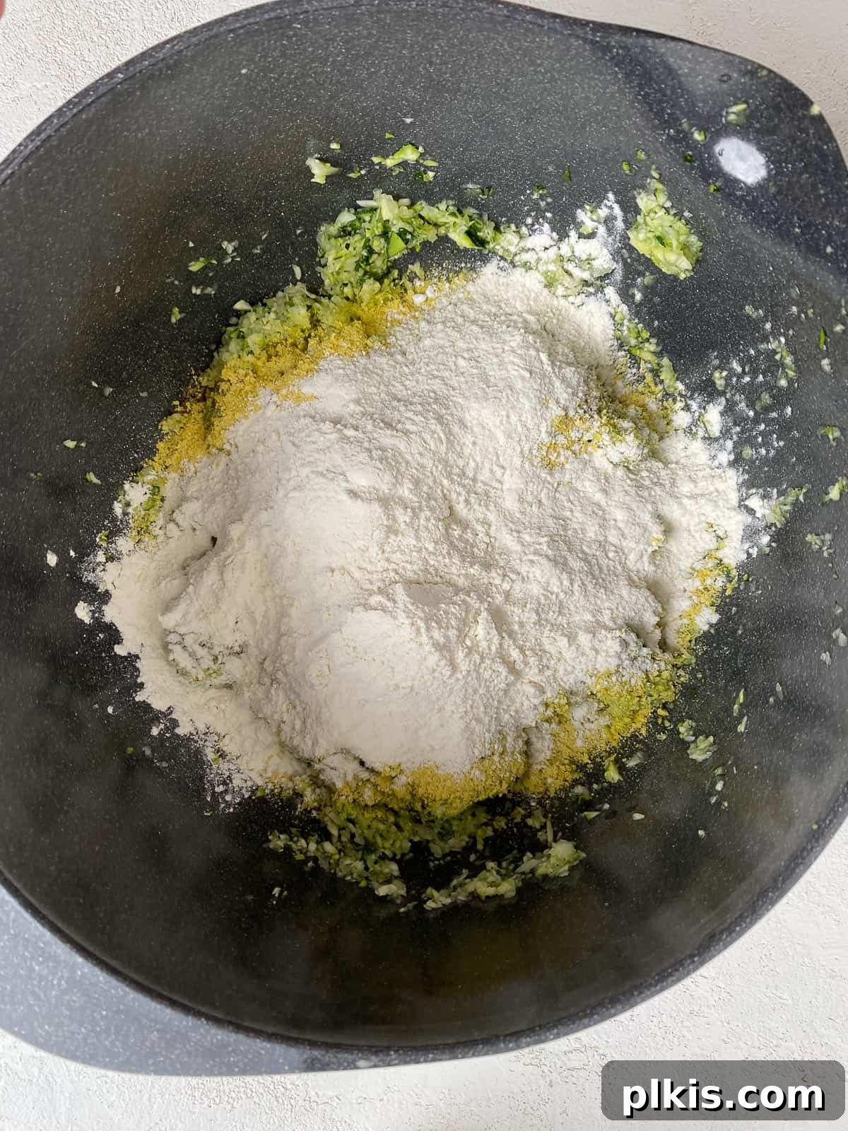 Wholesome Baked Plant-Based Zucchini Fritters 9 flour added to bowl of zucchini mixture
