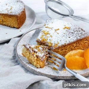 A completed slice of Orange Olive Oil Cake, beautifully plated against a white background, highlighting its moist and rich texture.