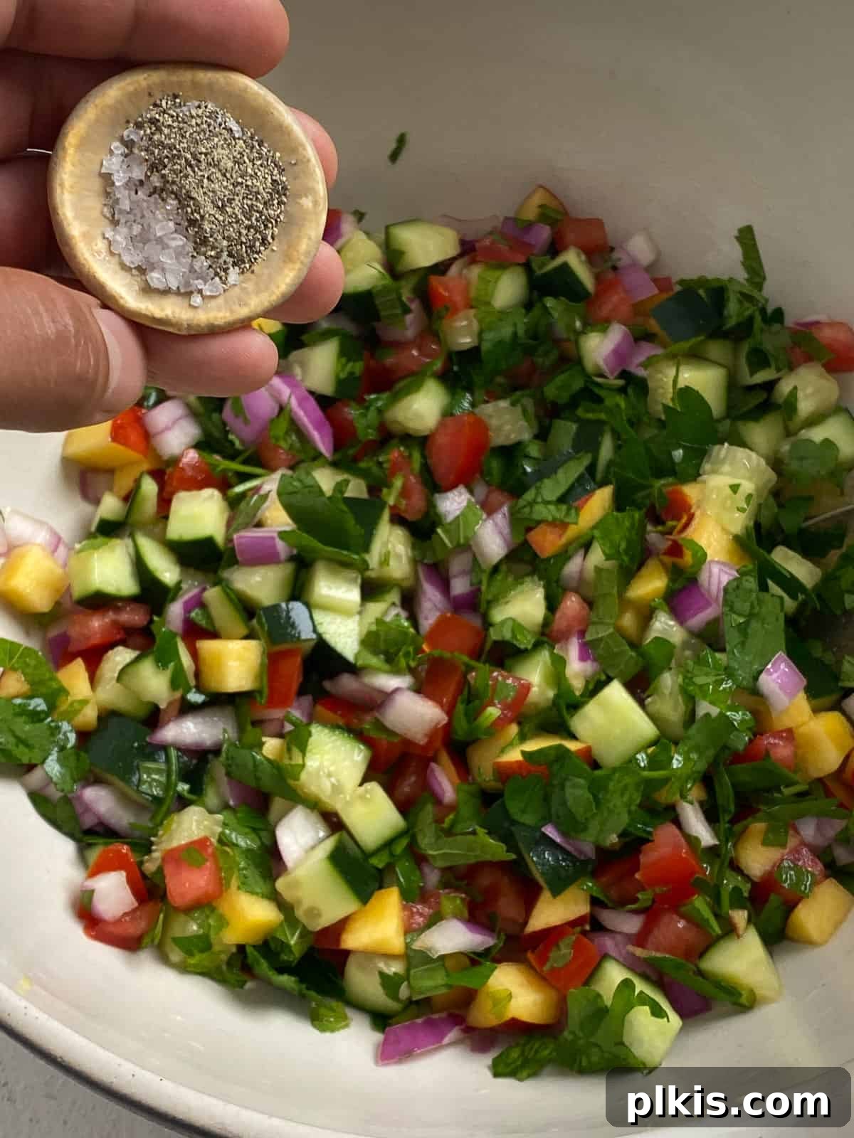 Zesty Fattoush Crunch 8 Salt and pepper being added to bowl of veggies