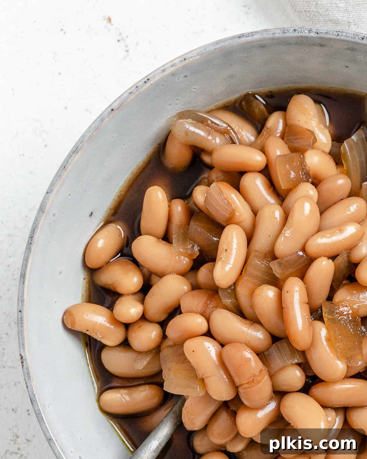 Homestyle Vegan Slow Cooker Baked Beans 2 Completed Vegan Slow Cooker Baked Beans in a white bowl against a white background, garnished with fresh herbs