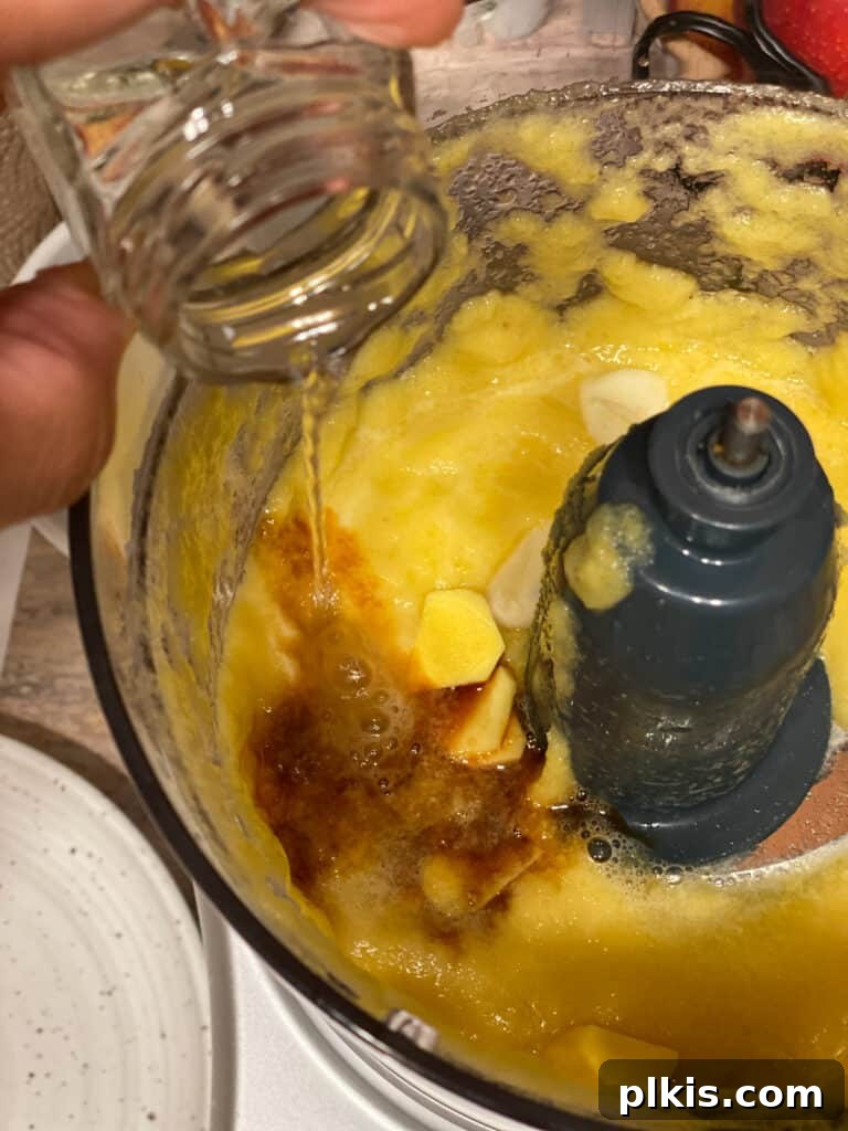 Process shot of adding rice wine vinegar to the food processor for the sauce.