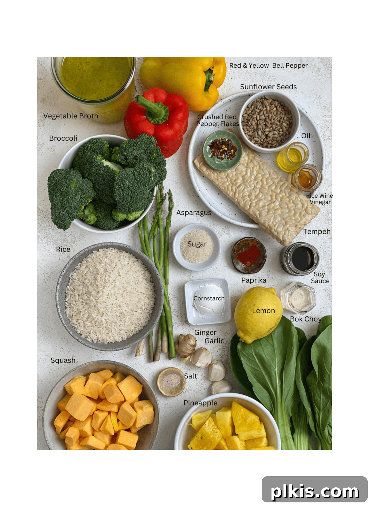 A vibrant flat lay showcasing all the fresh ingredients for Sweet and Sour Tempeh, meticulously measured out and arranged on a clean white surface.
