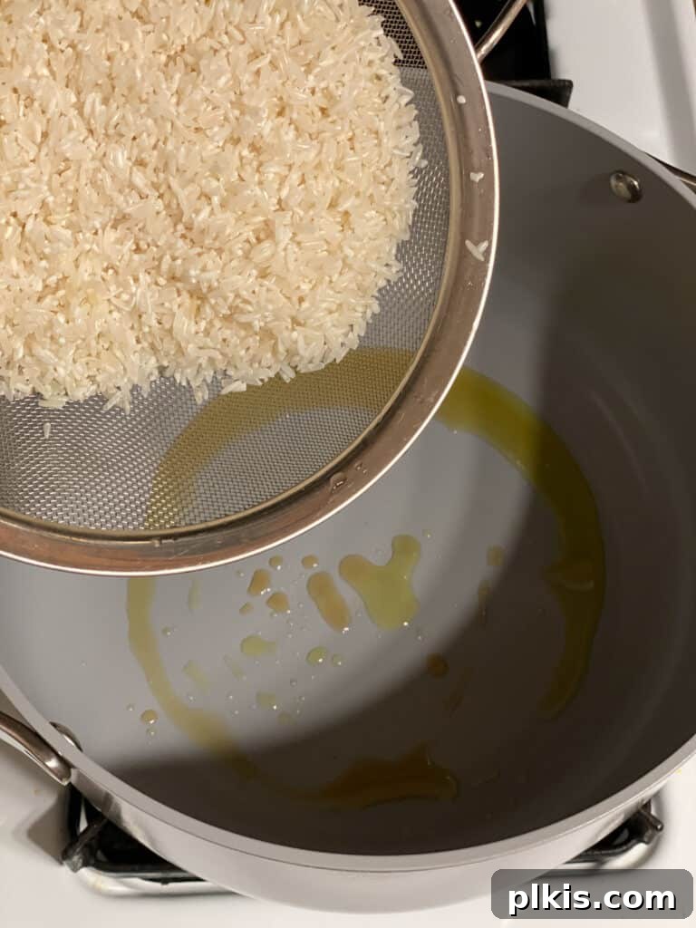 Process shot of adding raw rice to a hot pot with oil, preparing to toast it.