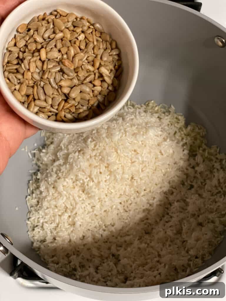 Process shot of adding sunflower seeds to the pot with rice, ready for toasting.