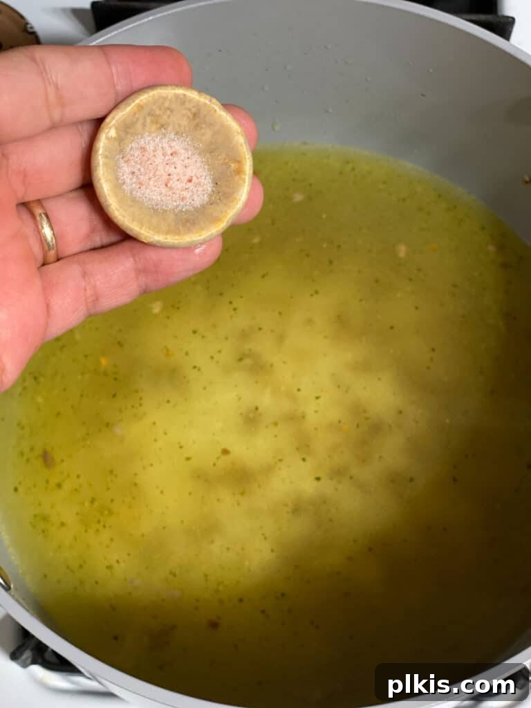 Process shot of adding a pinch of salt to the rice and vegetable stock mixture in the pot.