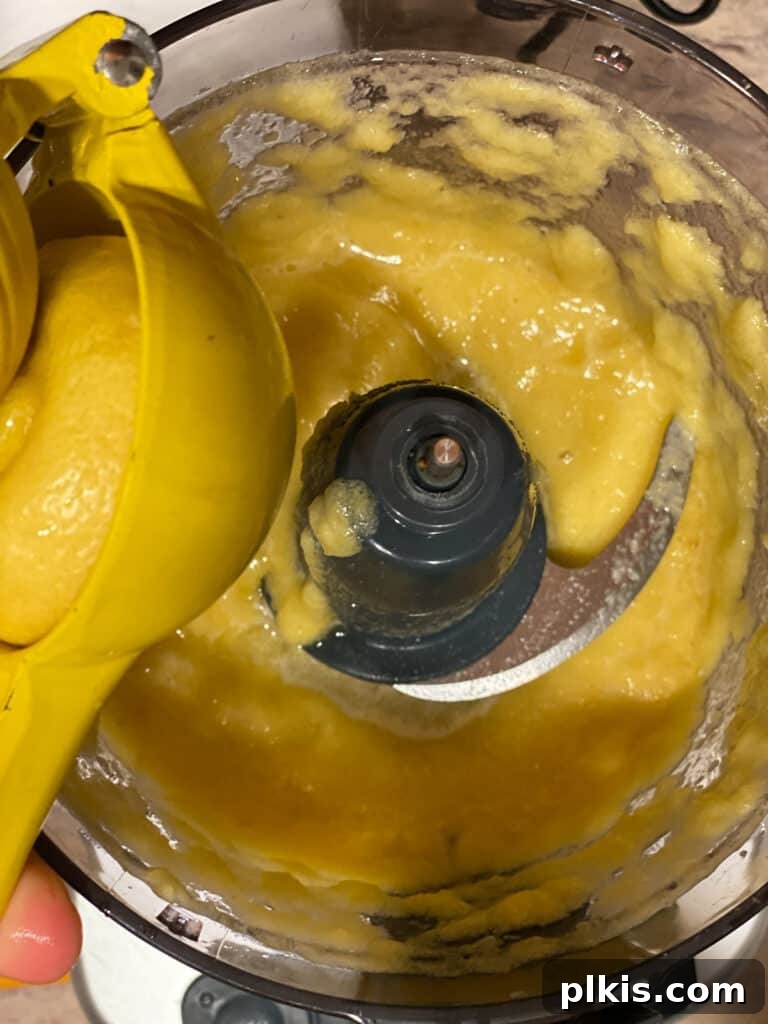 Process shot of adding lemon juice to the food processor with pineapple puree.