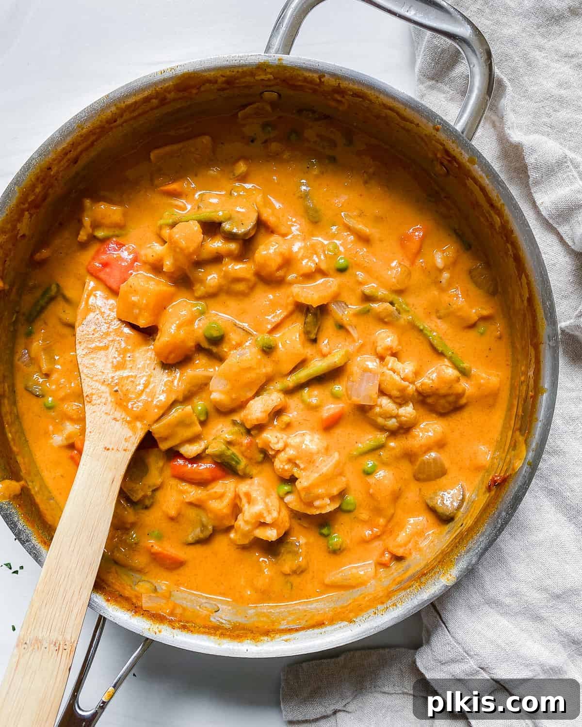 Golden Butternut Curry 9 completed butternut squash curry in pot with wooden spoon against light background