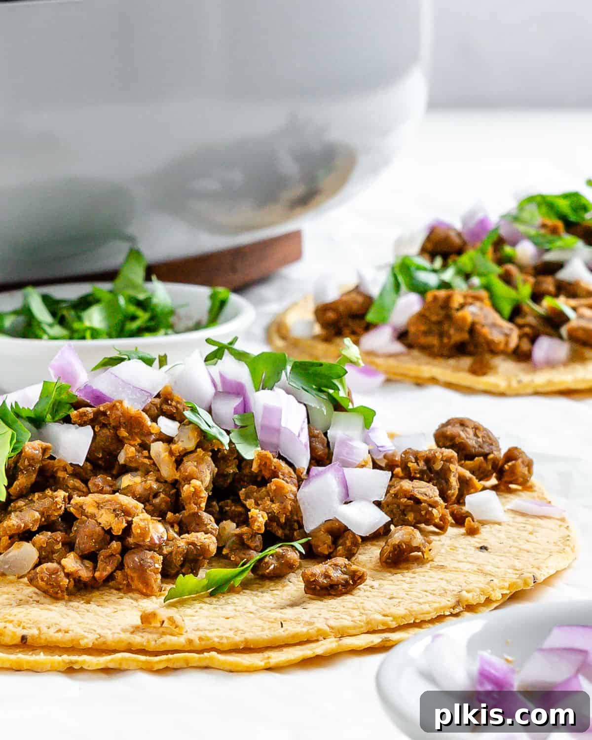 Hearty Plant-Based Lentil Street Tacos 16 completed Plant Based Street Tacos with Lentils on a white surface with ingredients in the background