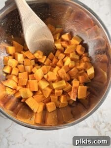 Curried Butternut Squash Roast 7 Step 4: Cubed butternut squash being tossed with oil and spices on a baking sheet