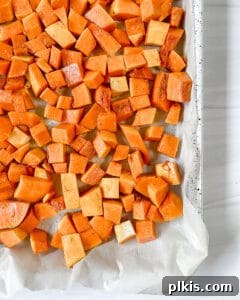 Curried Butternut Squash Roast 8 Process photo showing roasted butternut squash being stirred on a baking sheet mid-roast